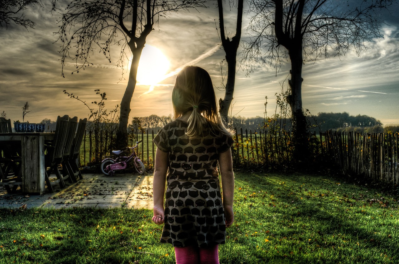 Girl alone looking out at dark backyard to represent eldest daughter syndrome.