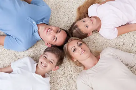 Family laying on carpet together representing family time that can help reduce childhood stress.