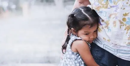 The effects of stress on the modern child represented by a young girl clinging on to her mother's side.