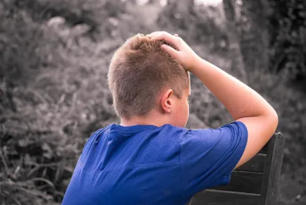 Young boy holding his head to represent the effects of stress on the modern child