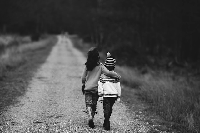 two childhood friends with arms around, walking down a country lane